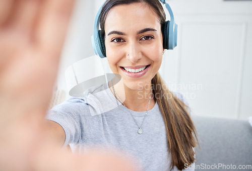 Image of Portrait of happy woman take selfie and smile with headphones while listening to music in the living room. Young beautiful lady streaming a podcast at home and relax in lounge and express happiness