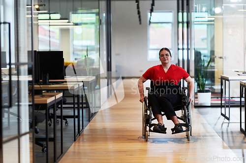 Image of A modern young businesswoman in a wheelchair is surrounded by an inclusive workspace with glass-walled offices, embodying determination and innovation in the business world