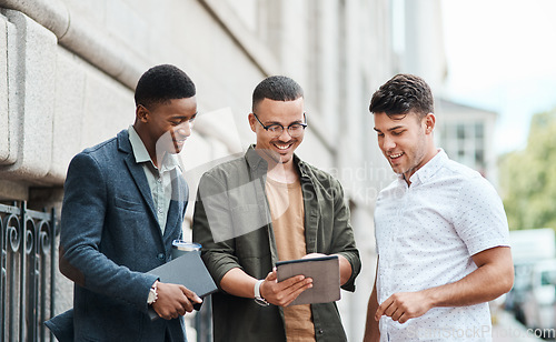 Image of Casual group of IT engineers preparing for a meeting on a digital tablet outside together. Diverse team of happy technicians talking and reading plans and strategy for a startup or project