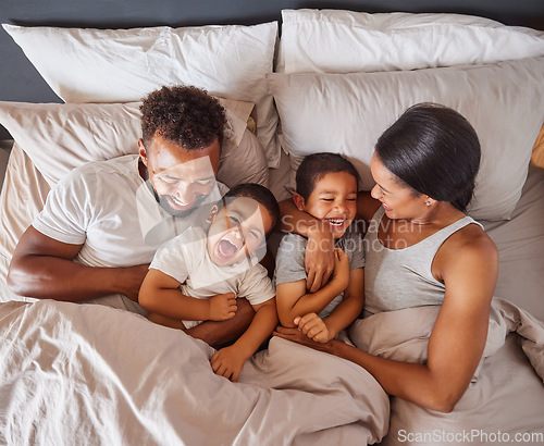 Image of Happy family bonding in bed together, playing and laughing while being loving and having fun. Young caring interracial parents sharing special moment of parenthood with two playful boys in bedroom