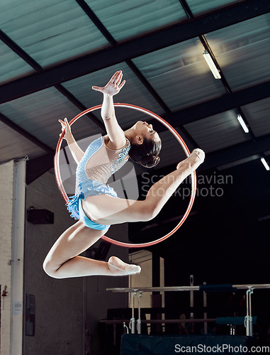 Image of Sports woman, performance and ring in the air for gymnastics show. Fitness girl doing artistic pose and stretch for acrobat stunt. Young and beautiful athlete in gym with hula hoop and flexible body.