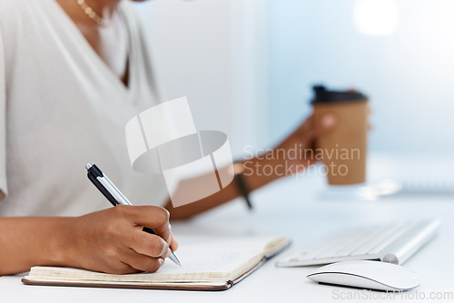Image of A business woman writing notes in a notebook or managing her schedule in a diary or completing a journal in an office. Closeup of an assistant working on a notepad learning from the internet