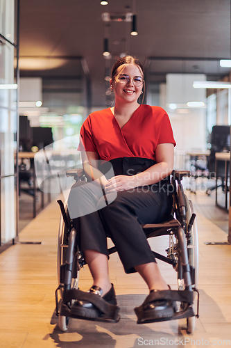 Image of A modern young businesswoman in a wheelchair is surrounded by an inclusive workspace with glass-walled offices, embodying determination and innovation in the business world