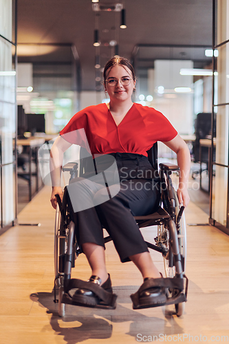 Image of A modern young businesswoman in a wheelchair is surrounded by an inclusive workspace with glass-walled offices, embodying determination and innovation in the business world