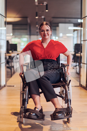 Image of A modern young businesswoman in a wheelchair is surrounded by an inclusive workspace with glass-walled offices, embodying determination and innovation in the business world