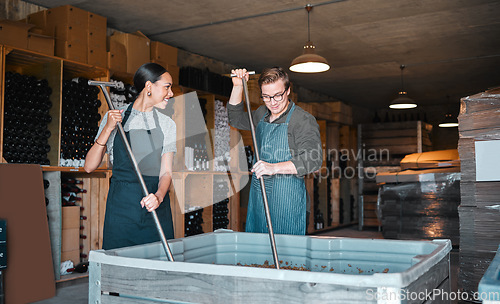 Image of Winery workers making wine with a fruit press tool or equipment in warehouse or distillery. Woman and man winemakers or factory people pressing juice of grapes manufacturing alcohol for the industry.