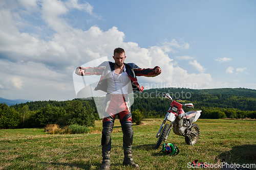 Image of A professional motocross rider, clad in a full suit, gloves, and backpack, prepares for a daring adventure through the forest, geared up for an adrenaline-pumping off-road journey