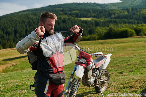 Image of A professional motocross rider, clad in a full suit, gloves, and backpack, prepares for a daring adventure through the forest, geared up for an adrenaline-pumping off-road journey