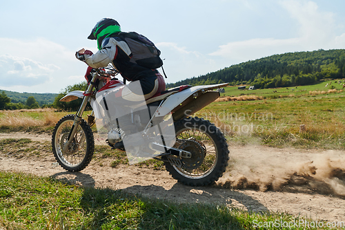 Image of A professional motocross rider exhilaratingly riding a treacherous off-road forest trail on their motorcycle.