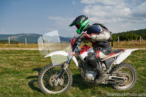 Image of A motorcyclist equipped with professional gear, rides motocross on perilous meadows, training for an upcoming competition.