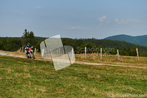 Image of A professional motocross rider exhilaratingly riding a treacherous off-road forest trail on their motorcycle.