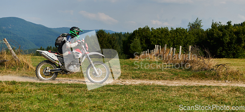 Image of A professional motocross rider exhilaratingly riding a treacherous off-road forest trail on their motorcycle.