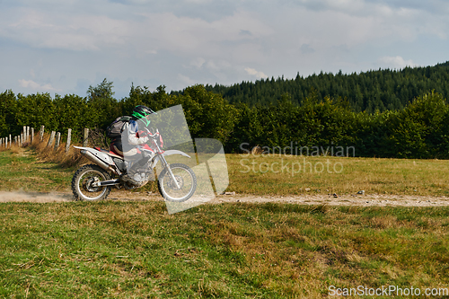 Image of A professional motocross rider exhilaratingly riding a treacherous off-road forest trail on their motorcycle.