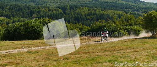 Image of A professional motocross rider exhilaratingly riding a treacherous off-road forest trail on their motorcycle.