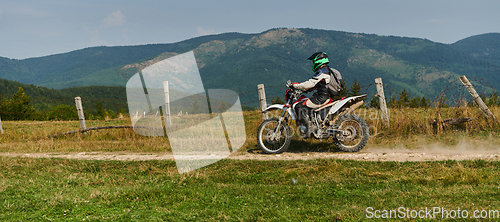 Image of A professional motocross rider exhilaratingly riding a treacherous off-road forest trail on their motorcycle.