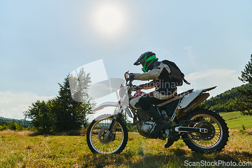 Image of A motorcyclist equipped with professional gear, rides motocross on perilous meadows, training for an upcoming competition.