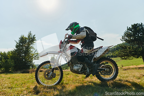 Image of A motorcyclist equipped with professional gear, rides motocross on perilous meadows, training for an upcoming competition.