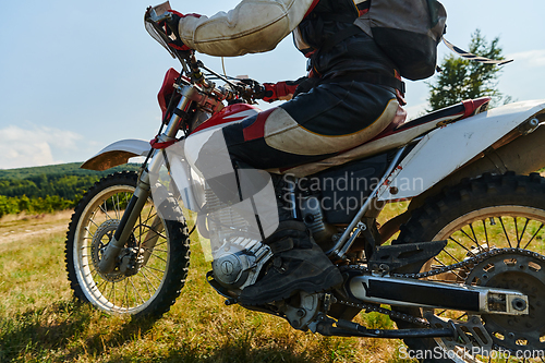 Image of A motorcyclist equipped with professional gear, rides motocross on perilous meadows, training for an upcoming competition.