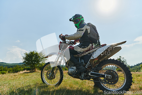 Image of A motorcyclist equipped with professional gear, rides motocross on perilous meadows, training for an upcoming competition.