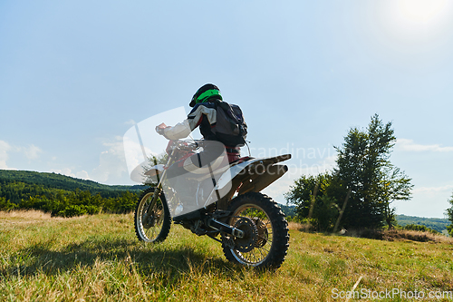 Image of A motorcyclist equipped with professional gear, rides motocross on perilous meadows, training for an upcoming competition.