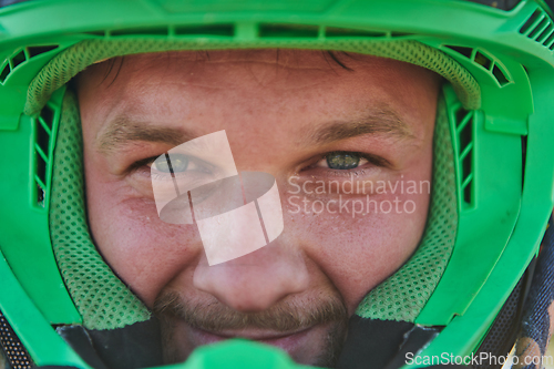 Image of The determined face of a professional motocross rider, adorned with a protective helmet, reflects unwavering focus and readiness for an adrenaline-fueled adventure.