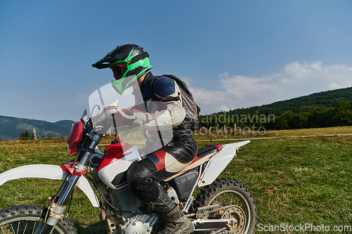 Image of A motorcyclist equipped with professional gear, rides motocross on perilous meadows, training for an upcoming competition.