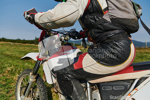 Image of A motorcyclist equipped with professional gear, rides motocross on perilous meadows, training for an upcoming competition.
