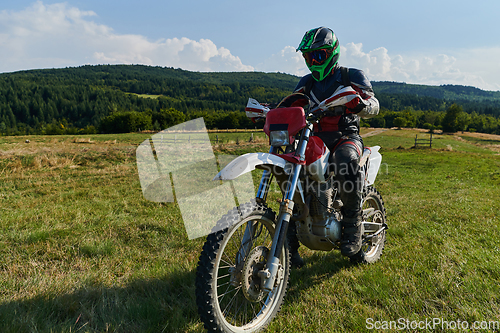 Image of A motorcyclist equipped with professional gear, rides motocross on perilous meadows, training for an upcoming competition.