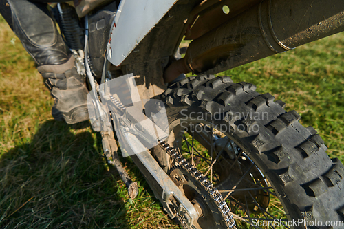 Image of Close up photo of a professional motocross rider in action, showcasing the tire and various components of the motorcycle as they navigate the challenging off-road terrain with speed and precision.