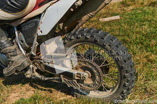 Image of Close up photo of a professional motocross rider in action, showcasing the tire and various components of the motorcycle as they navigate the challenging off-road terrain with speed and precision.