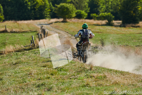 Image of A professional motocross rider exhilaratingly riding a treacherous off-road forest trail on their motorcycle.