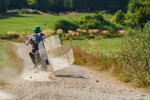 Image of A professional motocross rider exhilaratingly riding a treacherous off-road forest trail on their motorcycle.