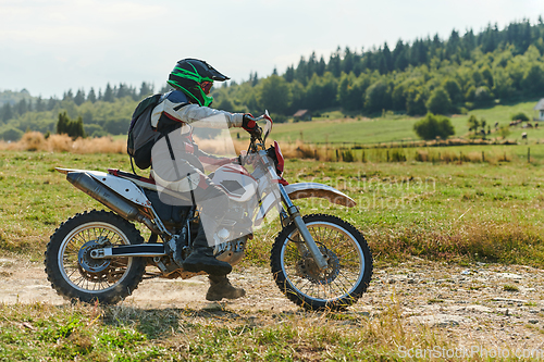 Image of A professional motocross rider exhilaratingly riding a treacherous off-road forest trail on their motorcycle.