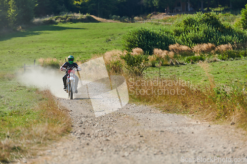 Image of A professional motocross rider exhilaratingly riding a treacherous off-road forest trail on their motorcycle.