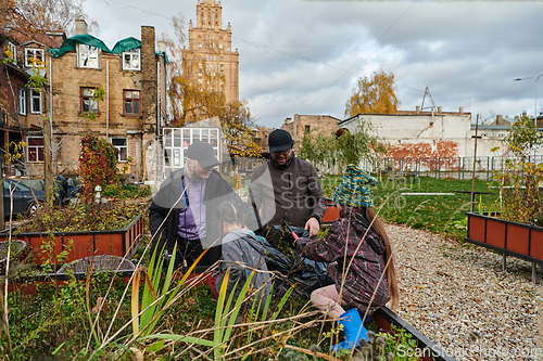 Image of A modern family parents and children, is working together to beautify their front yard with flowers in preparation for the upcoming holiday season.