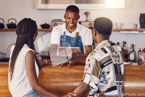 Image of Hospitality, service and technology with restaurant worker taking orders on a digital tablet, smiling and talking. Young employee manage customer payment on an online app, paying using the internet