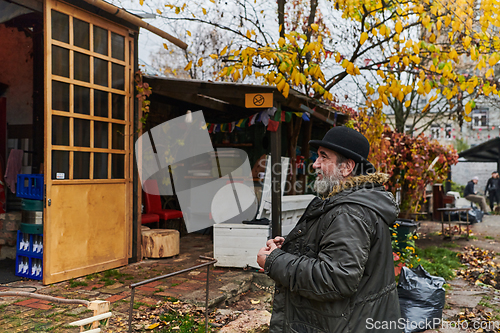 Image of In the historic city of Riga, a bearded elderly man passionately explains the traditional symbolism of Halloween, connecting generations through cultural heritage and folklore.