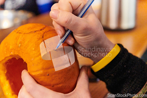 Image of A modern blonde woman in military uniform is carving spooky pumpkins with a knife for Halloween night