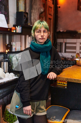 Image of A modern and intriguing girl with striking blue hair enjoys a night out in a cafe transformed into a passionate Halloween-style setting, exuding a captivating and witchy ambiance