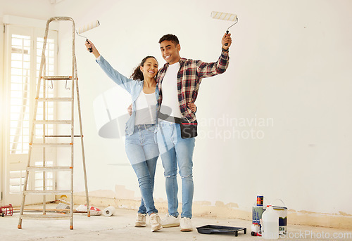 Image of Portrait of happy couple painting the new living room in a home or apartment. Man and woman with paintbrush to decorate a wall color and renovation the house interior with smile or happiness together