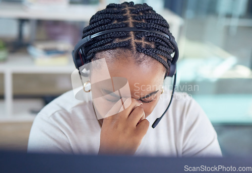 Image of Stress, burnout and sad call center agent with a headache and office overworked sitting in an office. Frustrated, sick or ill young black woman customer service employee with pain or migraine