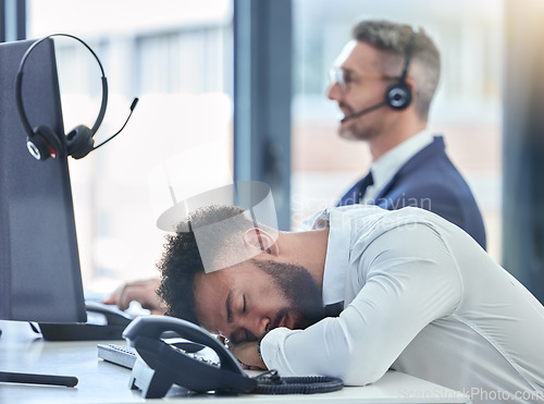 Image of Lazy, sleeping and tired call center agent at his table or desk at work overworked suffering from burnout. Exhausted young customer service employee asleep in the office or workplace