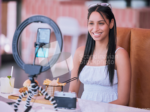 Image of Social media influencer online video of food at cafe, smartphone technology with mobile light lifestyle vlog. Happy young girl in restaurant with film camera, woman eating fries, burger and cocktail