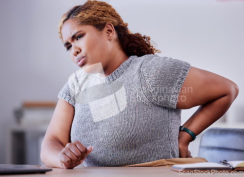 Image of Corporate employee suffering from back pain while working at a desk in an office, uncomfortable and concerned. Young professional experience discomfort from an injury, bad posture or hurt muscle