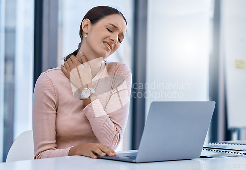 Image of Stress woman suffering from neck pain working on a laptop in a modern office. Corporate professional with bad posture and an injury. Business SEO worker with discomfort from long hours at a desk