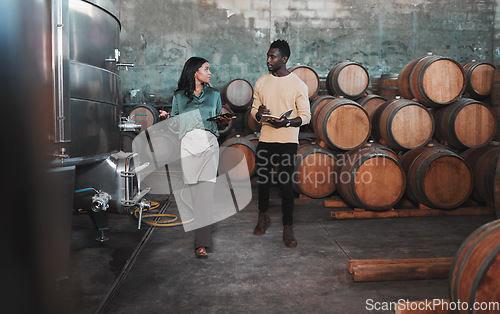 Image of Wine cellar, warehouse and winery worker teaching a man about wine while he is writing notes. Winemaker walking in a distillery with wooden barrels and agriculture machines while consulting a partner