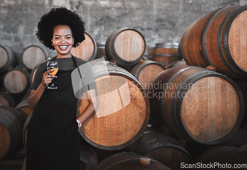 Image of Portrait of a young woman winemaker standing with a glass with wooden barrel of red wine in a winery cellar or distillery. Entrepreneur or business owner working for startup success business success