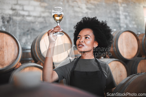 Image of Black woman tasting wine at a winery, looking and checking the color and quality of the years produce. Young African American sommelier proud of the new addition, analyzing white wine in a cellar