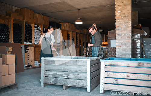 Image of Vintners, wine merchants and cellar workers in production cellar, winery and factory distillery for manufacturing. Industry staff working together to stir, mix and crush an open tank and big crate