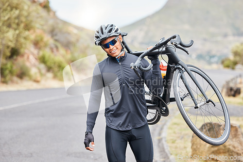Image of Cycling, bike trail and fitness man carrying his bicycle after riding along a countryside road. Happy male cyclist and athlete wearing a helmet, glasses and gear while training for a sports race